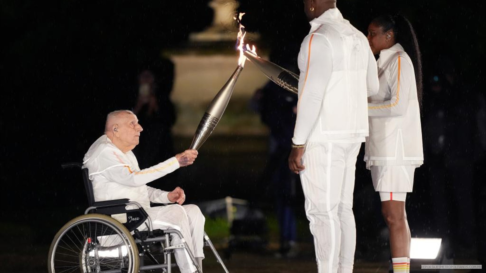 Charles Coste (izq.), campeón olímpico francés de mayor edad, pasa la llama olímpica a los portadores de la antorcha Marie-Jose Perec (dcha.) y Teddy Riner