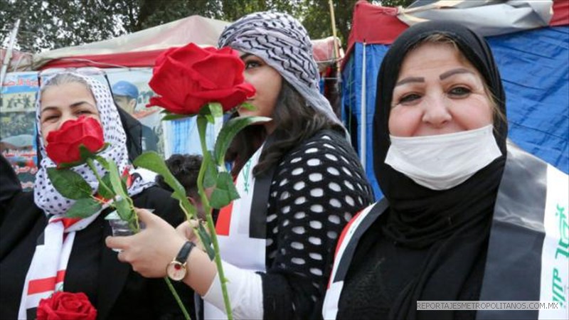 En Bagdad, Irak, las mujeres marchan con rosas, algunas llevan máscaras ante la amenaza del coronavirus.