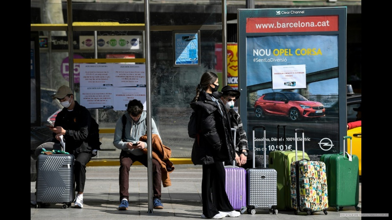 Turistas con máscaras faciales esperan el autobús del aeropuerto en Barcelona, el 15 de marzo de 2020
